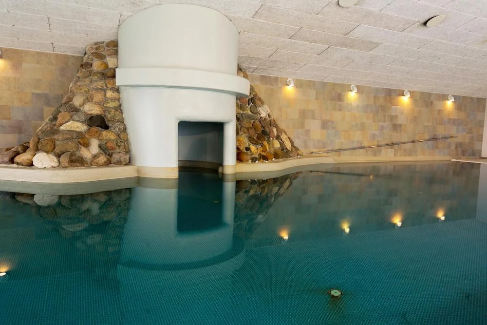 Indendørs swimmingpool i feriebolig i Skagen med unikt stendesign ved væggen.