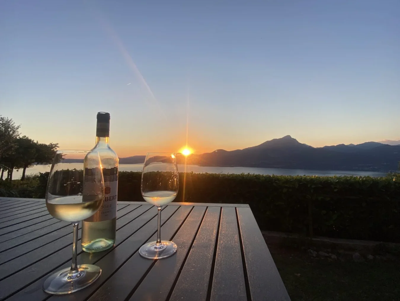 Solnedgang over Gardasøen set fra feriebolig i Torri del Benaco med vin på bordet